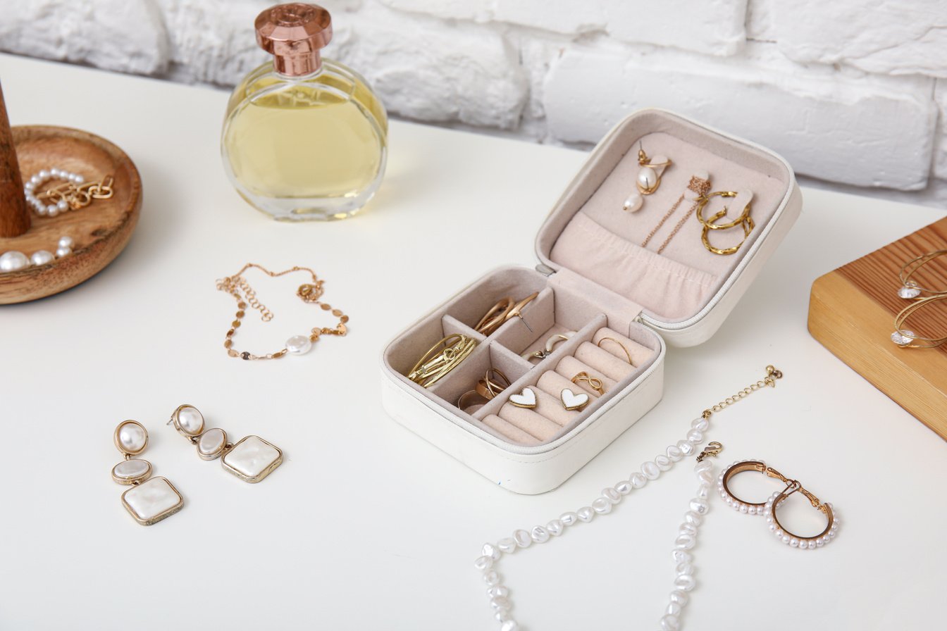 Box with Different Stylish Jewelry and Perfume Bottle on Dresser, Closeup